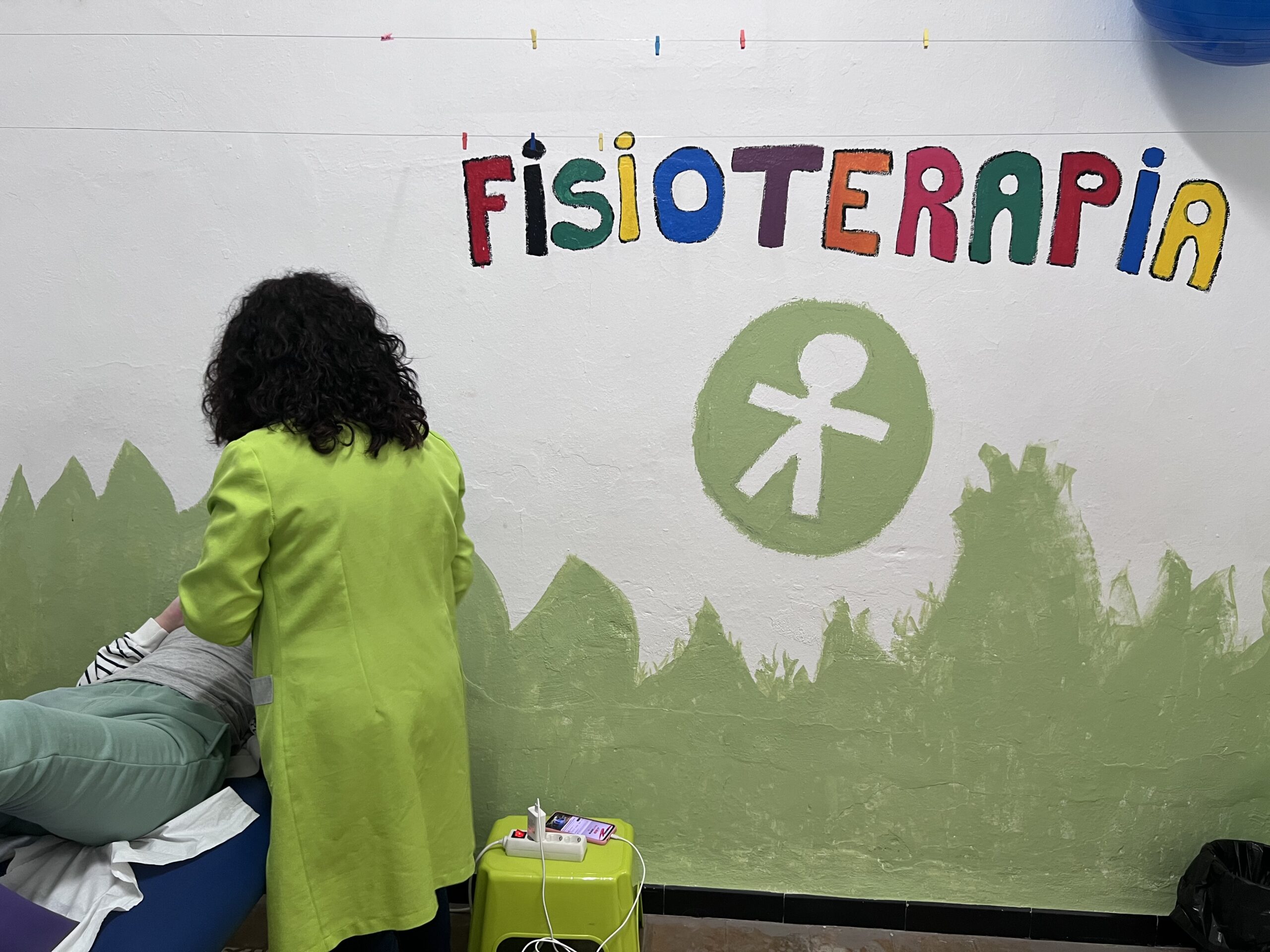 un profesional de la atención temprana ayuda a un niño a coger una figurita de papel situada en una zona alta